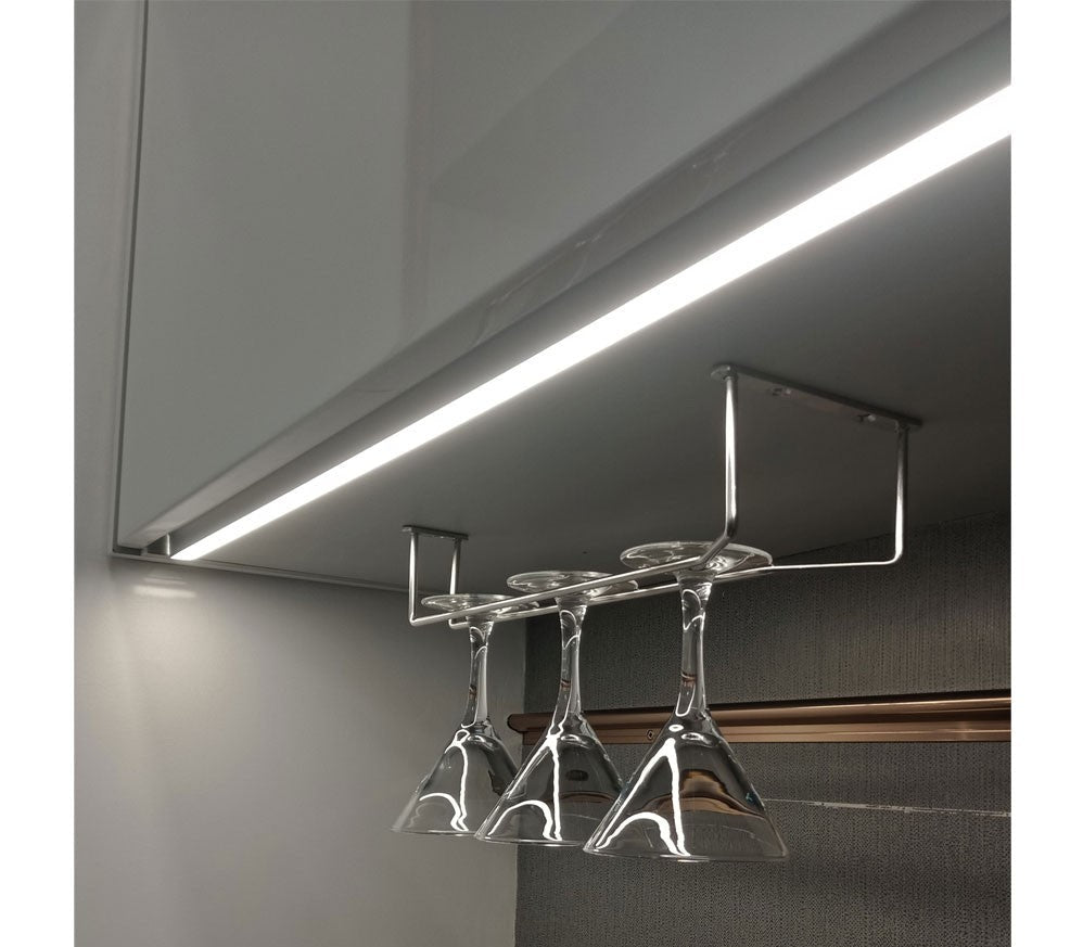 Under-cabinet wine glass holder with four glasses hanging from it, mounted on a kitchen cabinet.