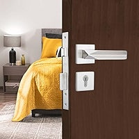 Close-up of a door handle on a wooden door with a bedroom in the background