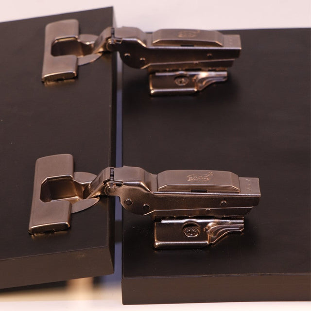 Metallic cabinet hinges on a black surface