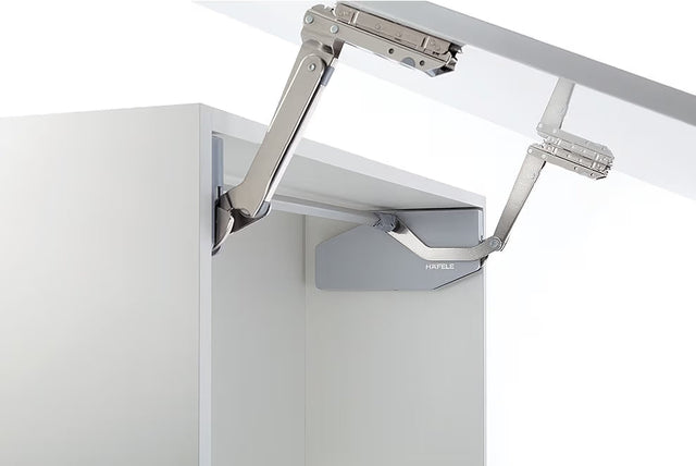 Metal cabinet hinge on a white cabinet door with a white background