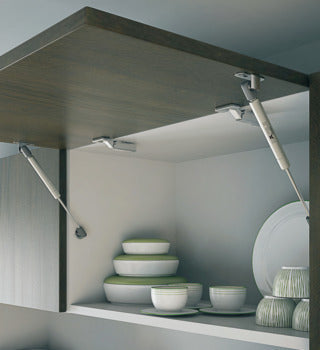 Open kitchen cabinet with green and white ceramic dishes inside