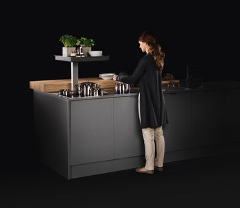 Person standing at a modern kitchen island with a black background