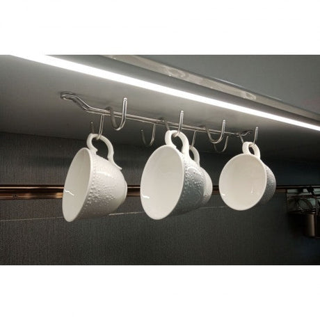 Three white textured cups hanging from a hook on a kitchen cabinet.